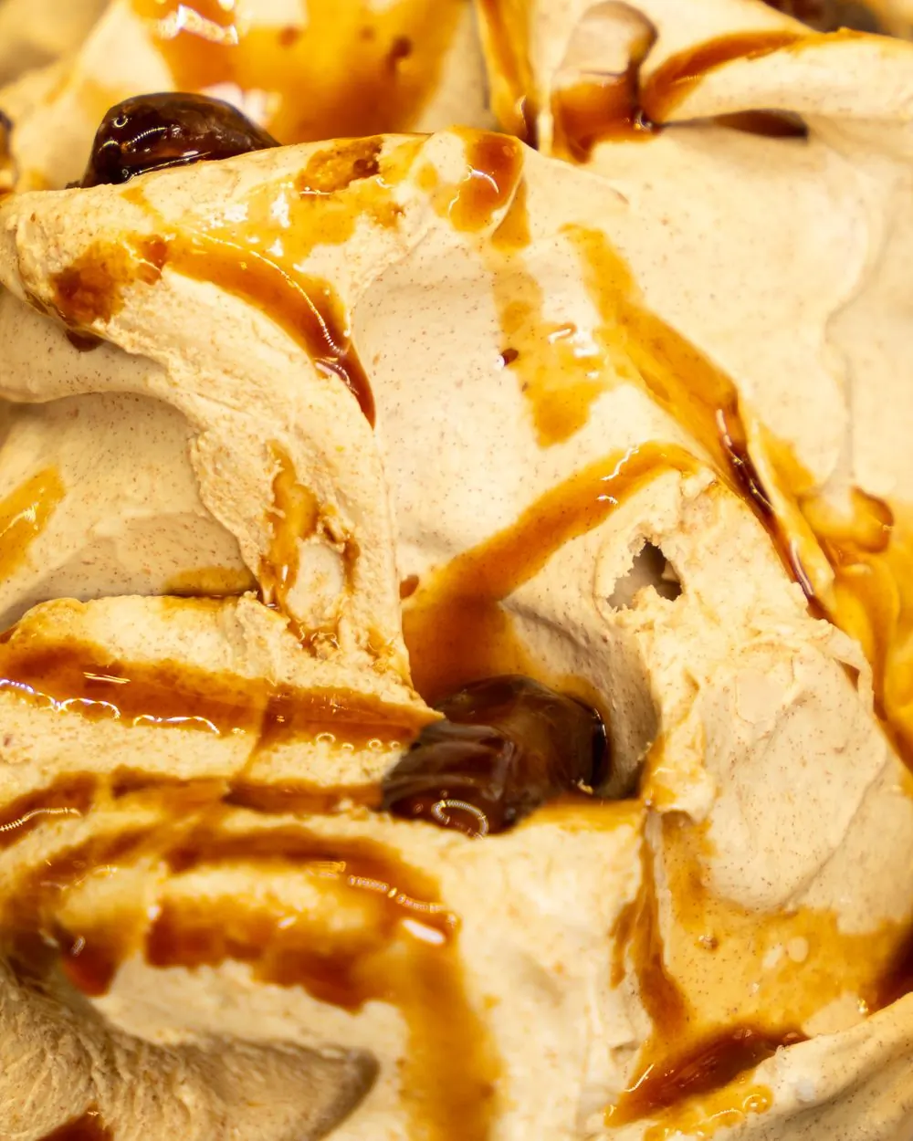 A caramel-coloured scoop shot through with dark flecks, in a shallow glass dish
