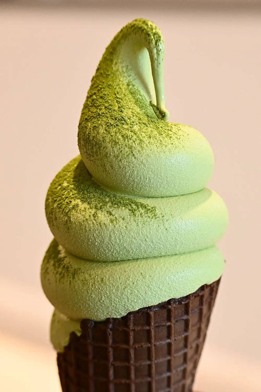 A pale green mint scoop flecked with dark chocolate, in a paper tub