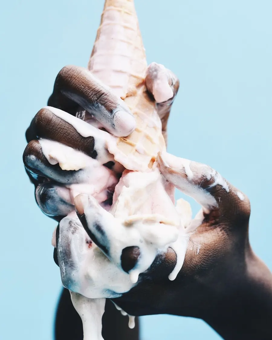 Two friends standing side by side, each holding a waffle cone in both hands