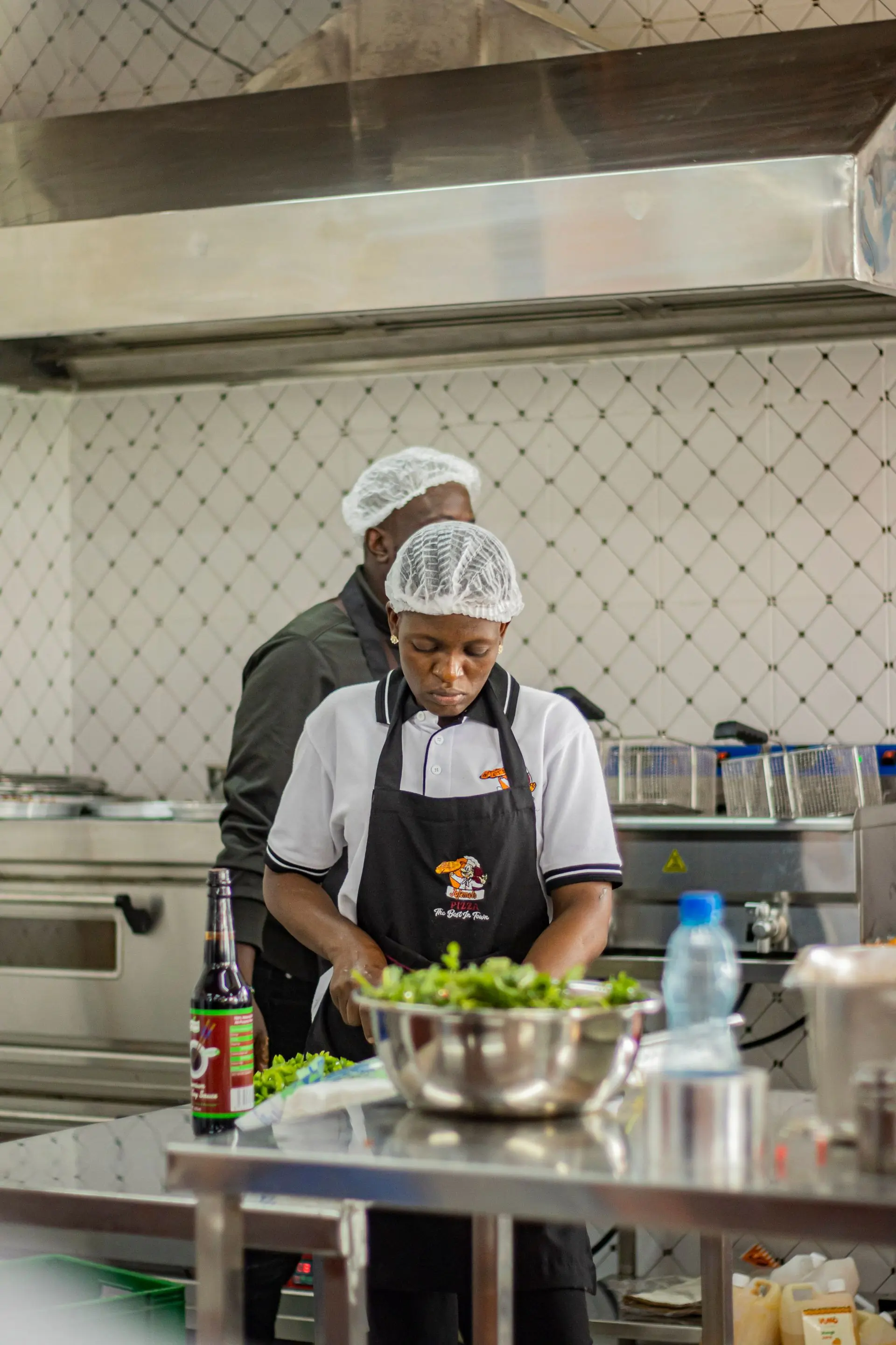 Two kitchen staff in aprons prepping fruit together at a stainless steel bench