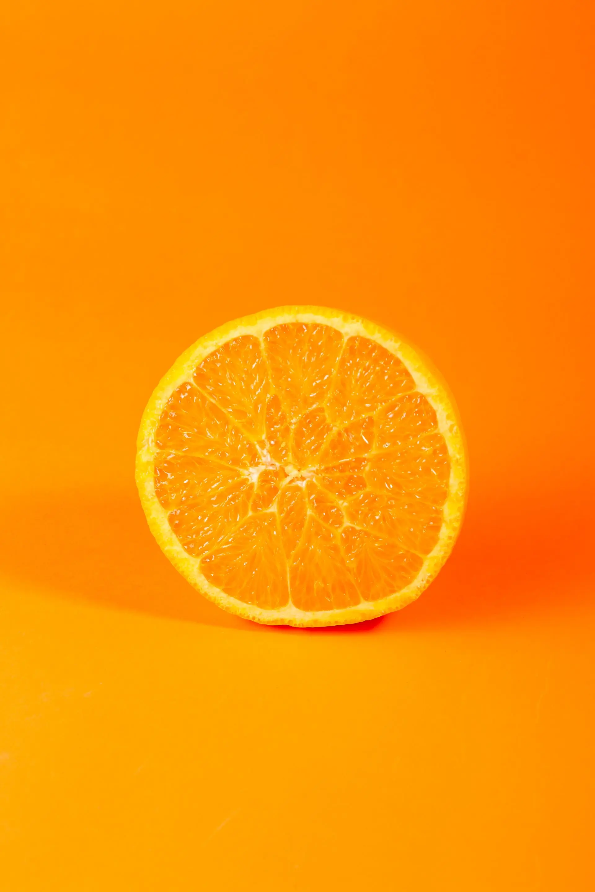 An orange half standing upright on a flat vivid orange ground