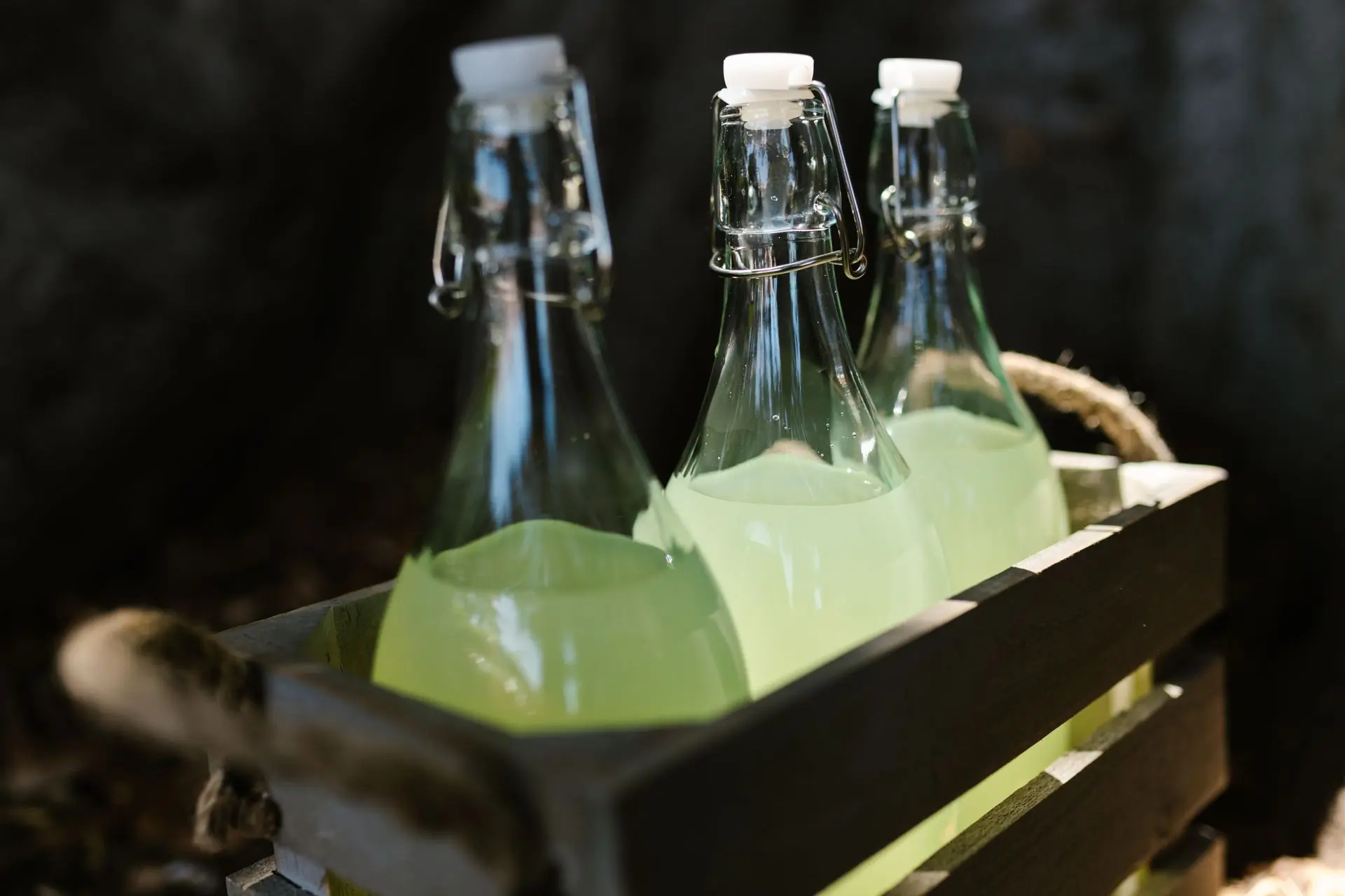 Flip top lemonade bottles packed in a green wooden crate