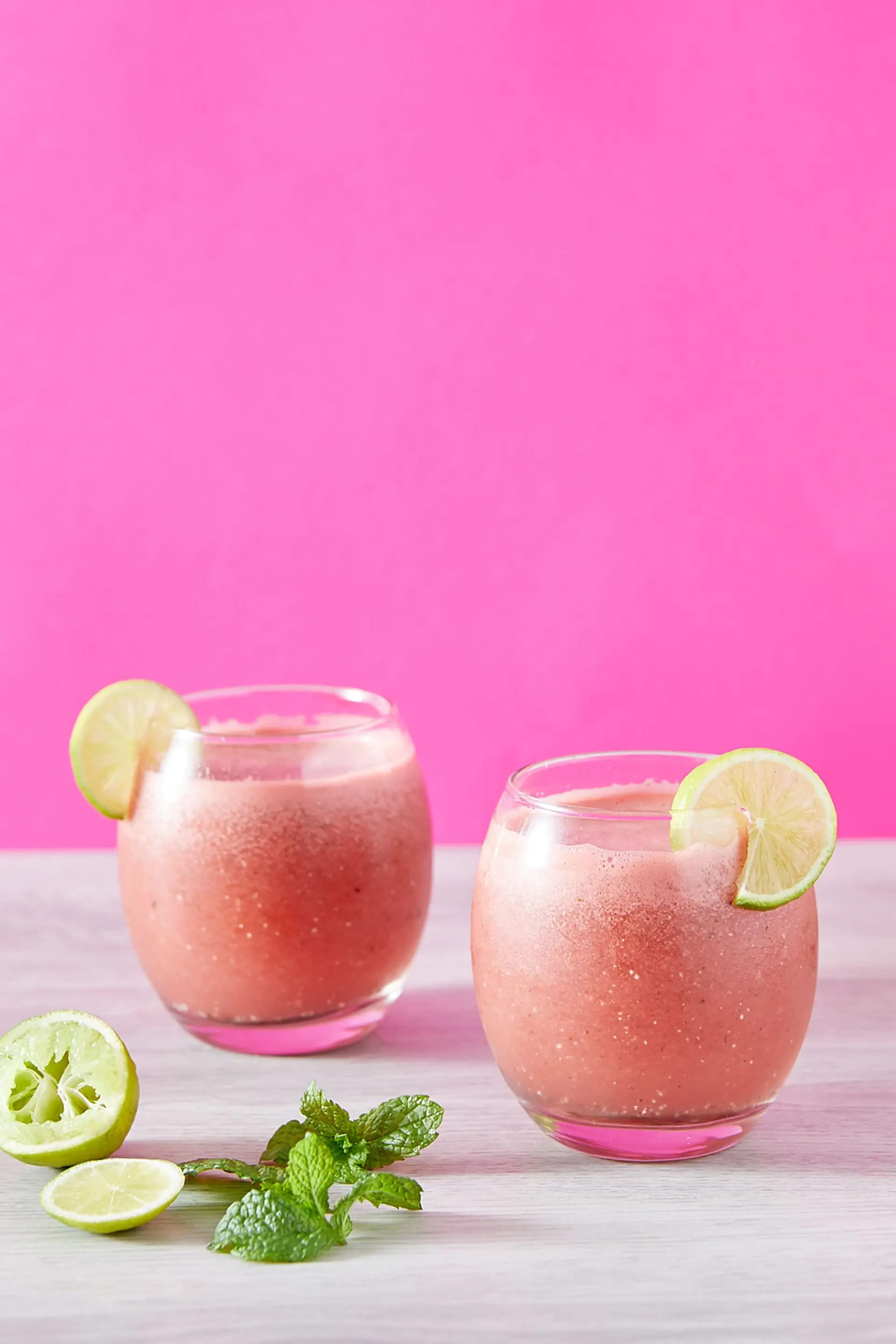 A tall pink blended drink dressed with fruit