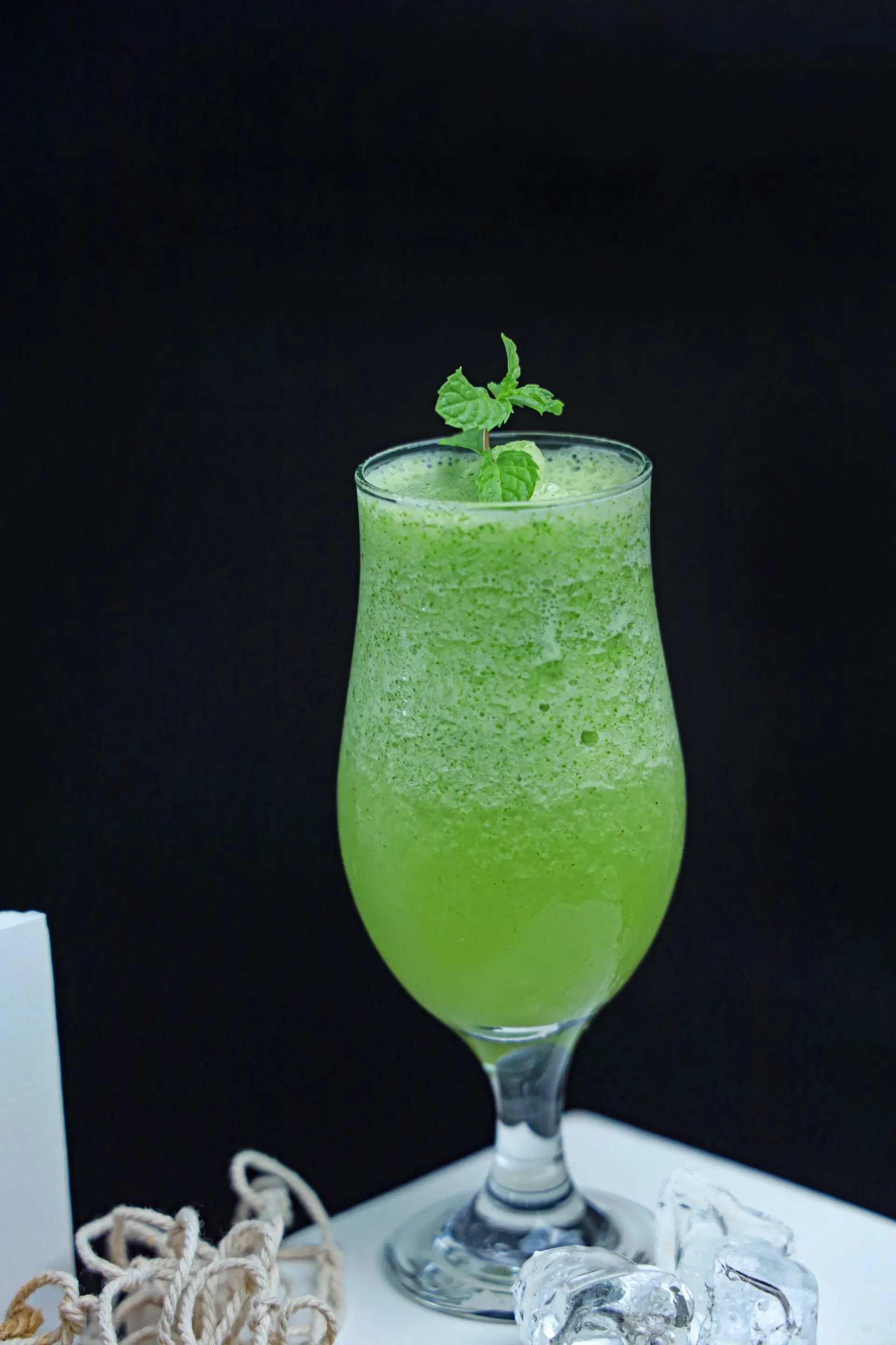 A green cooler with mint and kiwi in a clear glass