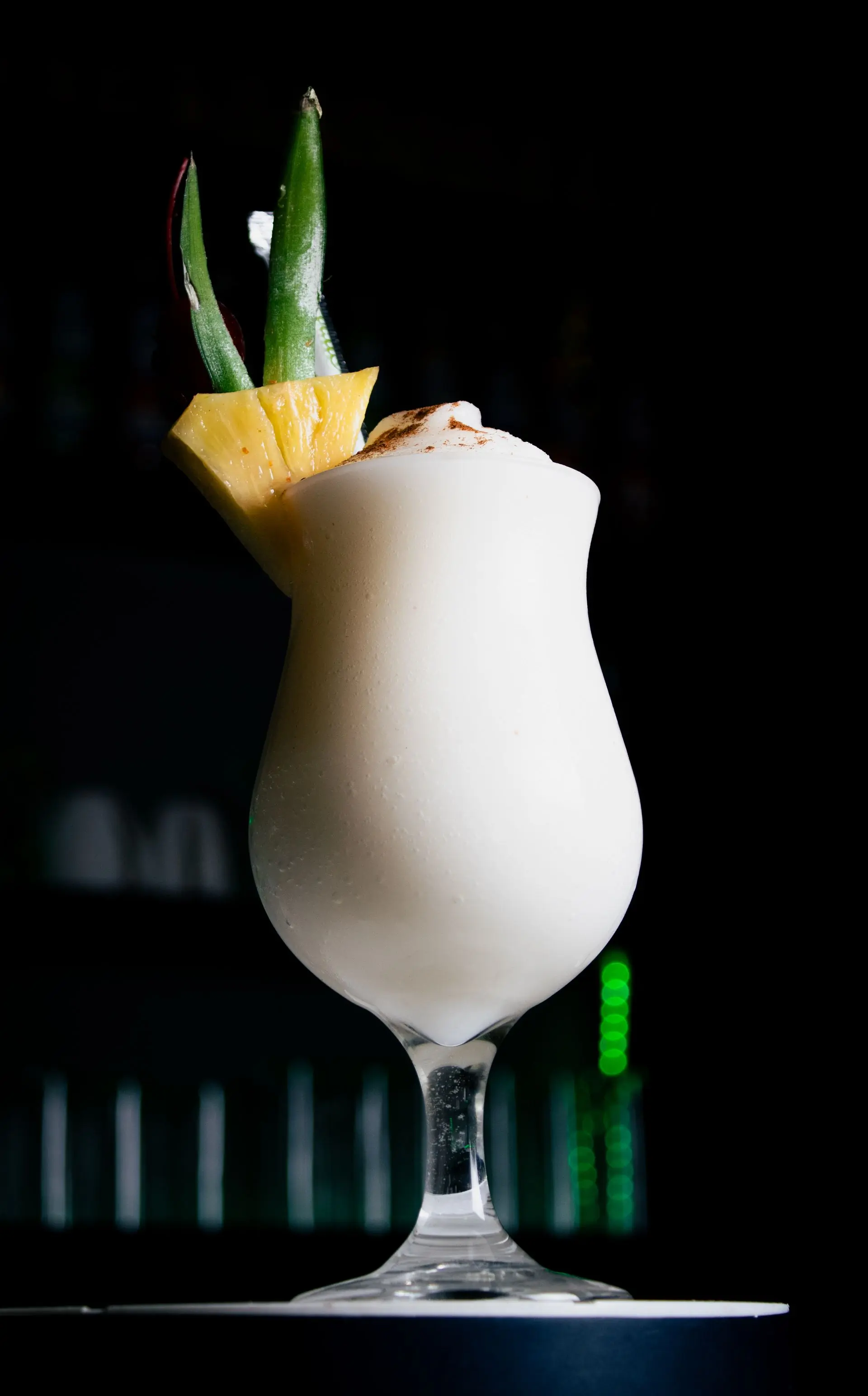 A fresh green coconut with a straw standing on a cool sea-green ground