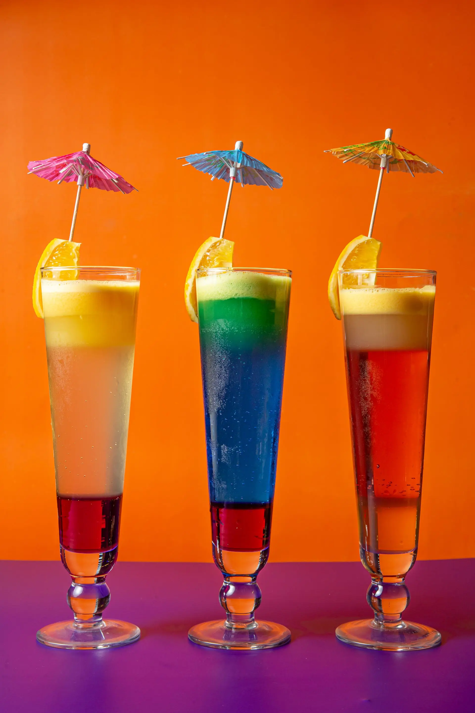 A line of six differently coloured fruit drinks standing together