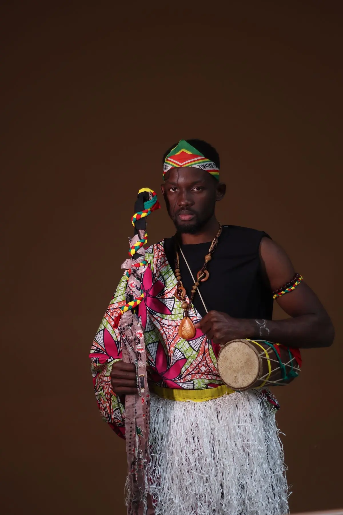 A drummer in colourful traditional dress playing at a cultural gathering