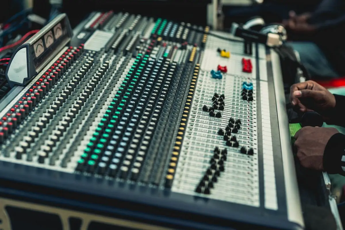 A professional audio mixing console lit from above in a studio