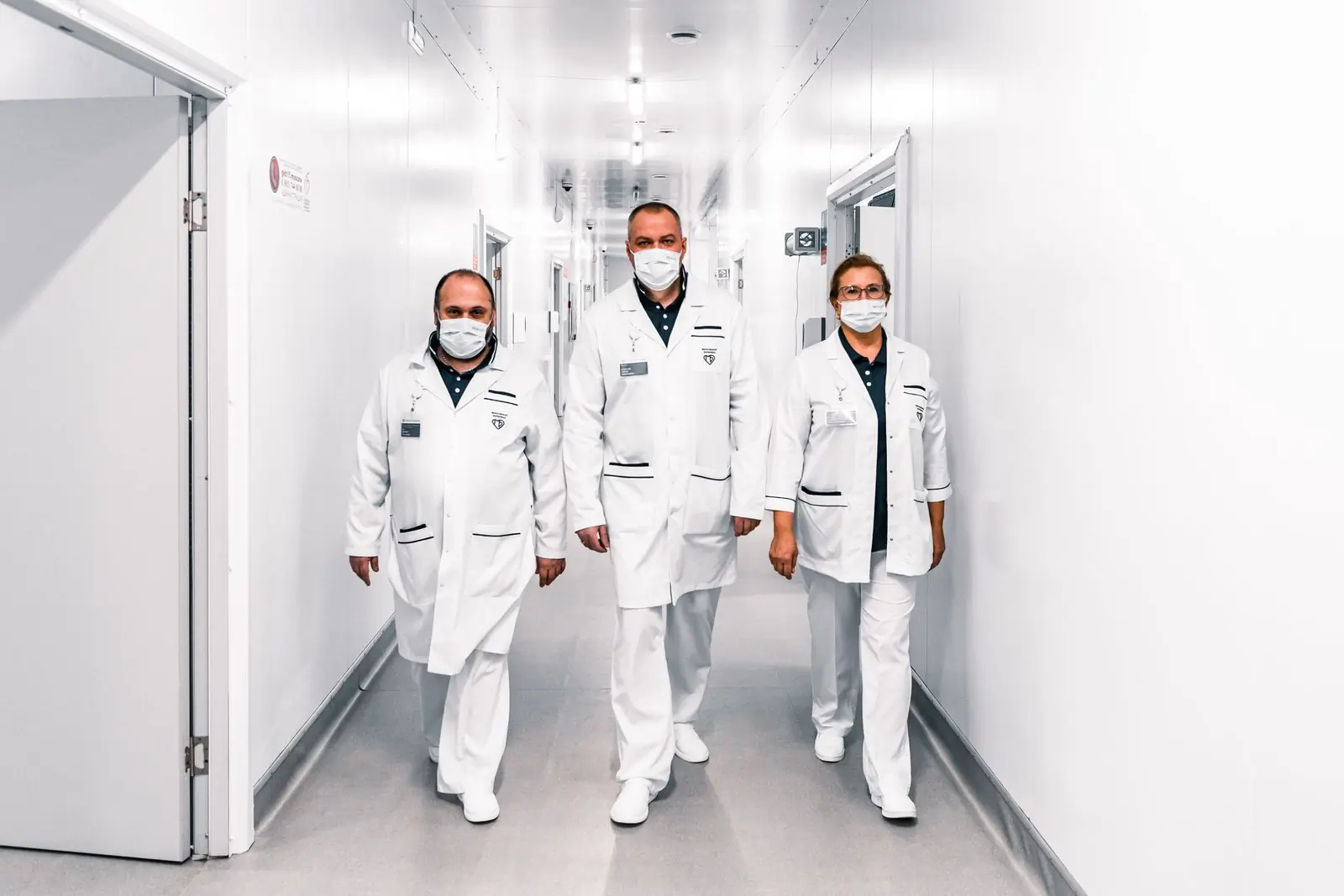 Three clinicians walking together through the centre's main corridor