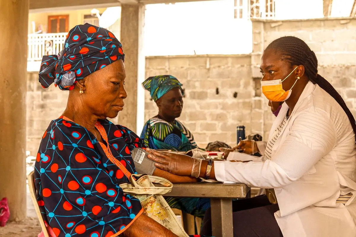 A community health worker checking an older woman's blood pressure