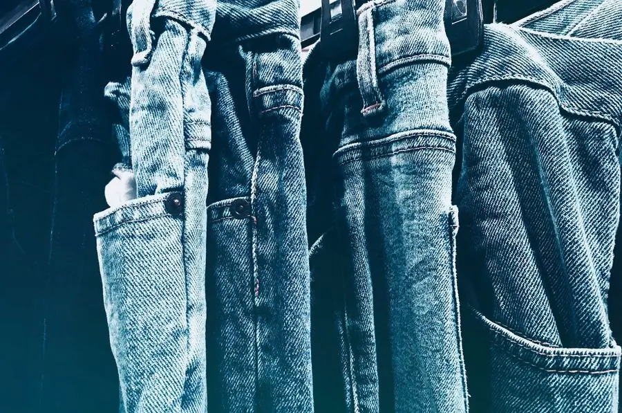 A close rail of blue jeans hung side by side