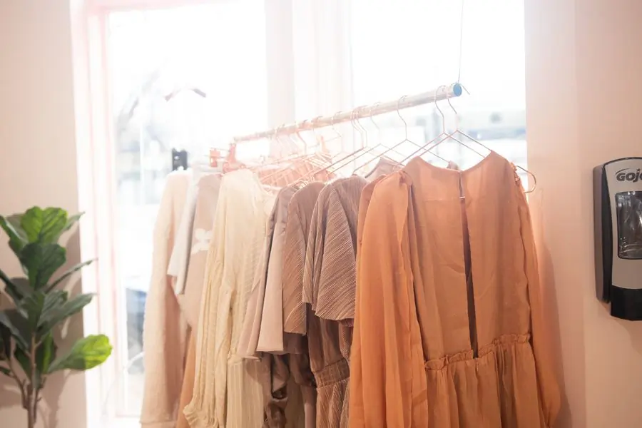 Peach and blush dresses on a rail lit from behind