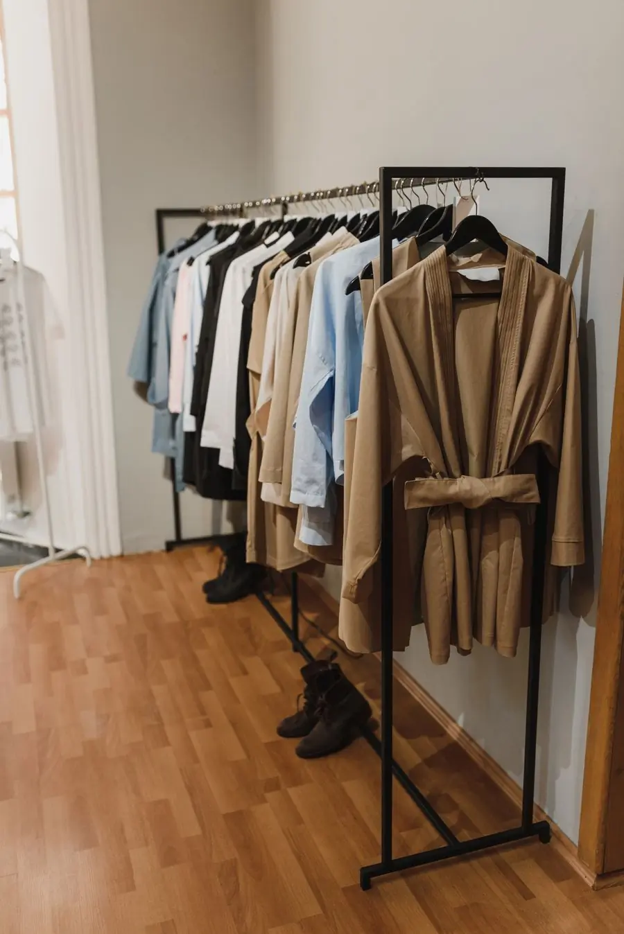 Trench coats and long jackets on a rail beside a window