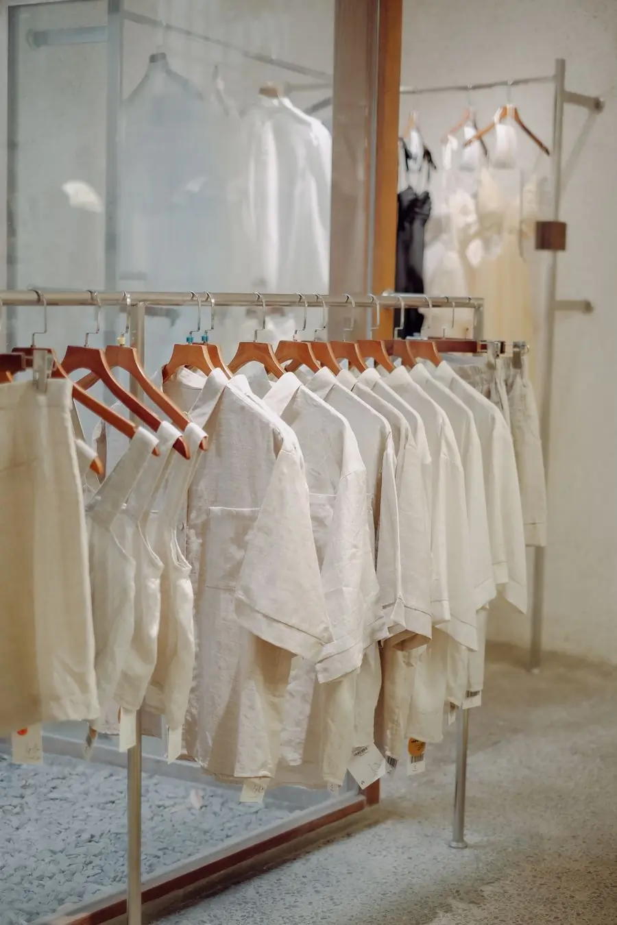 A rail of white and cream shirts on wooden hangers