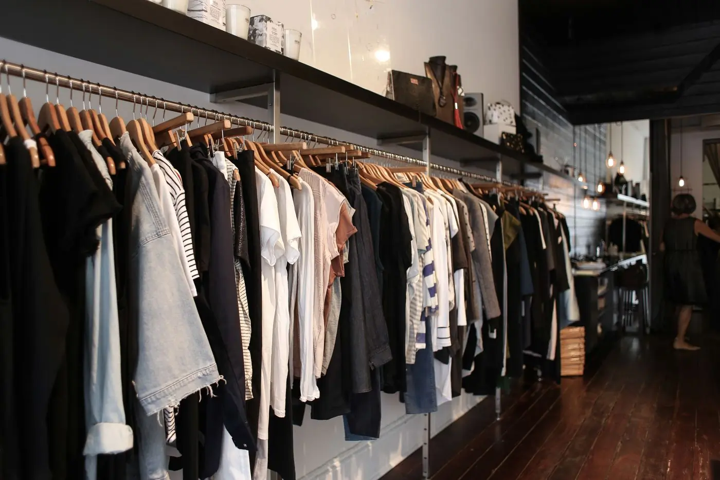 A long rail of darker pieces in a warm-lit shop