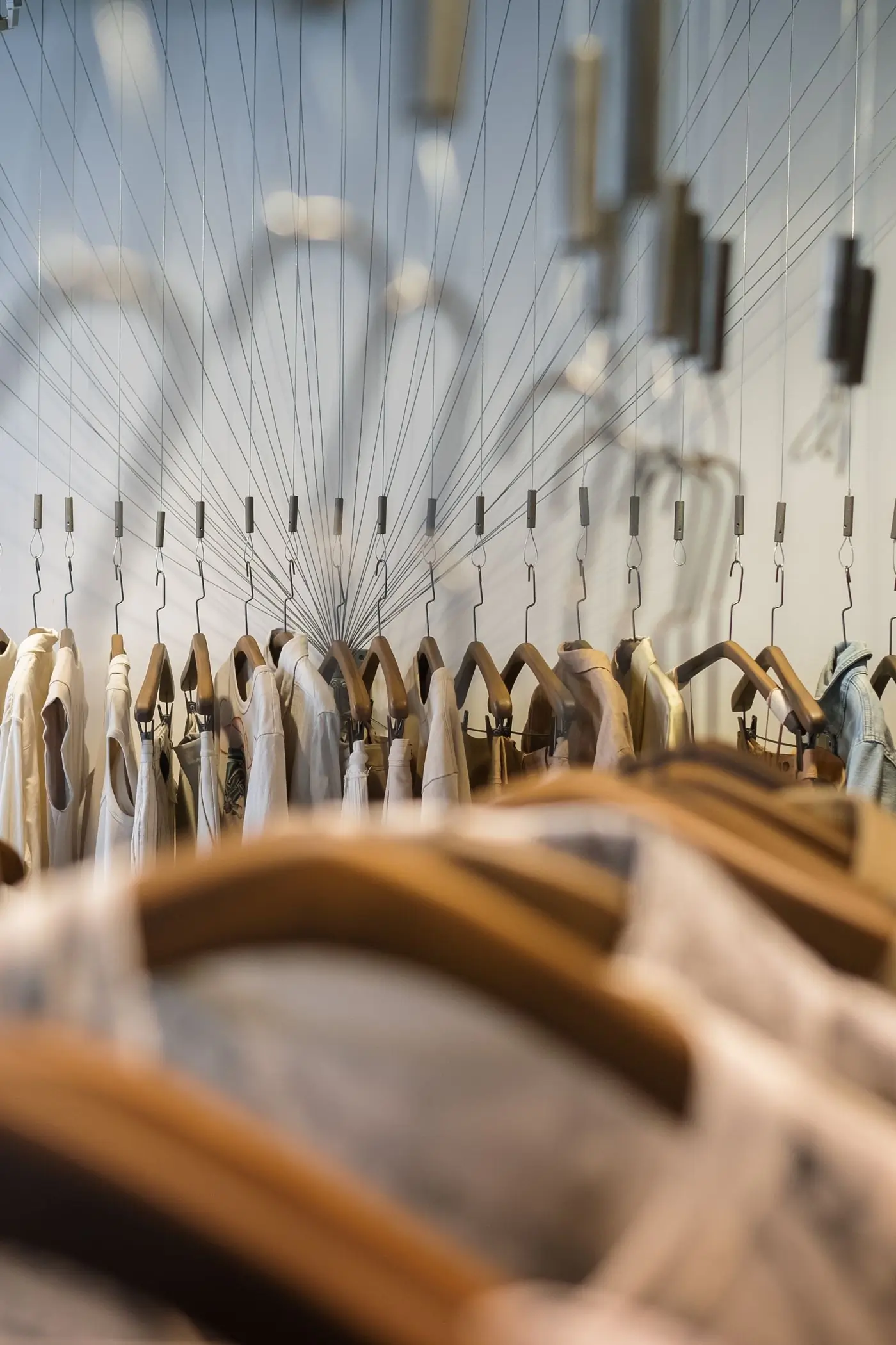 A long rail of pale garments on wooden hangers
