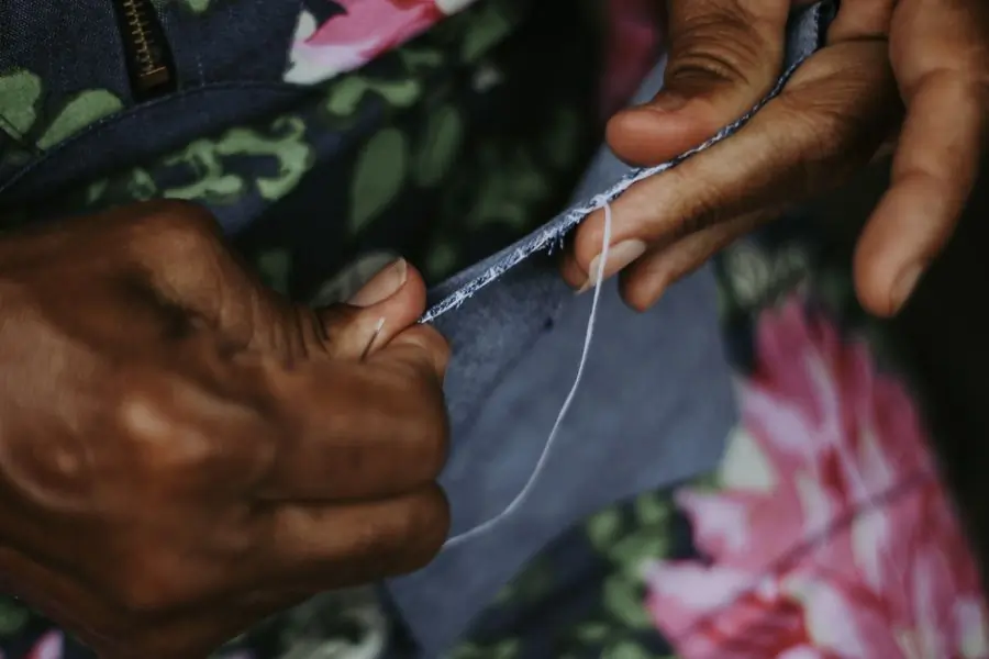 Hands sewing a hem by eye on printed cotton