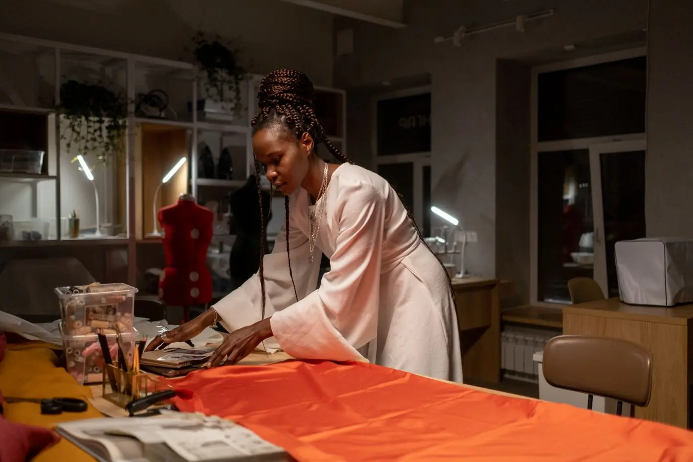 A designer laying out bright orange cloth on a studio table