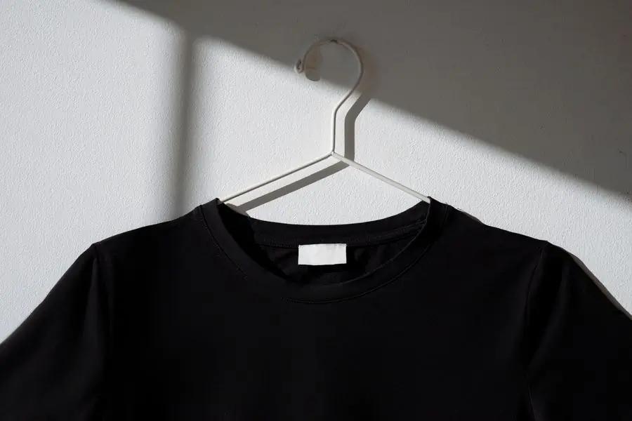 A black t-shirt on a wire hanger casting a long shadow