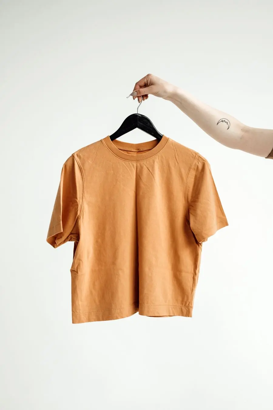 A boxy clay-orange t-shirt on a hanger