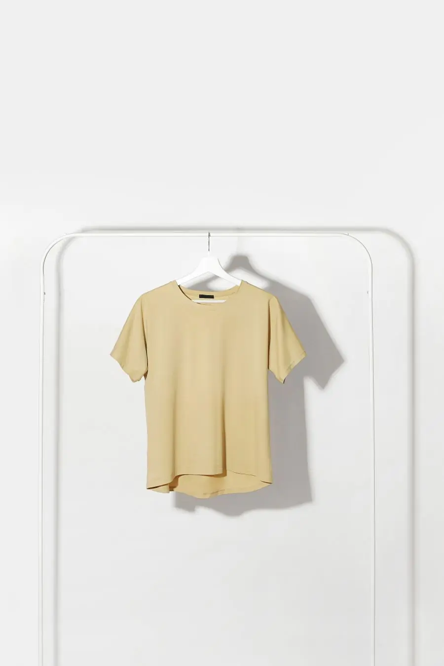 A pale butter-yellow t-shirt on a hanger