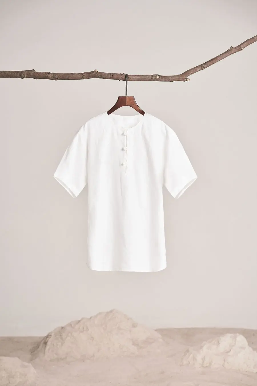 A white linen henley shirt on a warm neutral ground