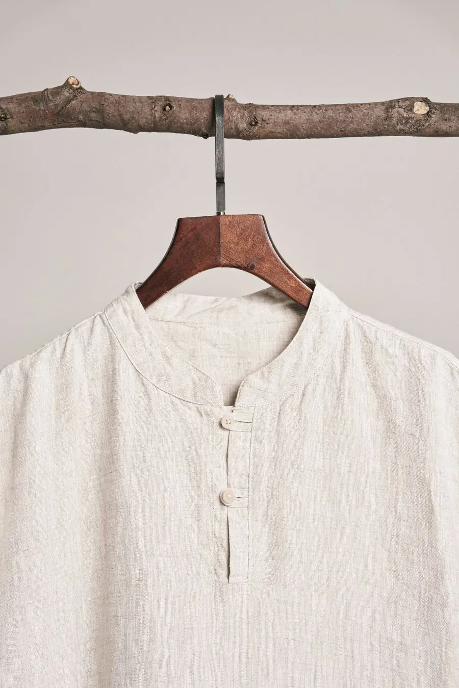 A natural linen grandad-collar shirt on a wooden hanger