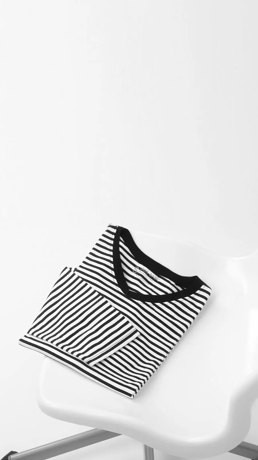 A black and white striped tee folded on a white chair
