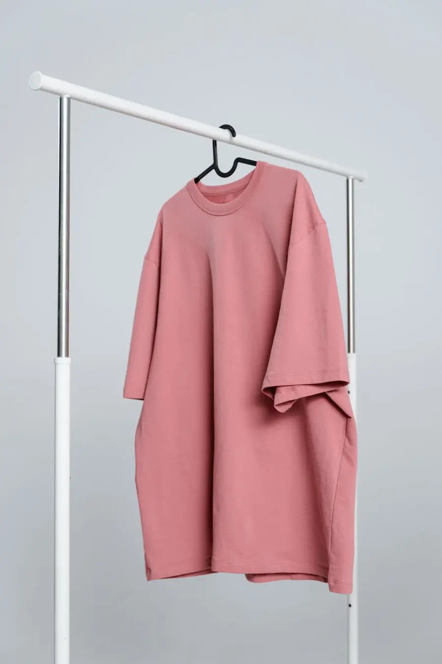An oversized rose-pink sweatshirt hanging on a rail