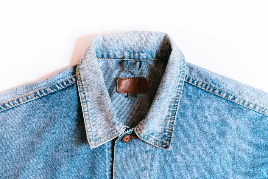 The collar of a pale washed denim trucker jacket