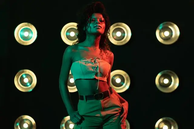 A model lit in red and green against a wall of bulbs