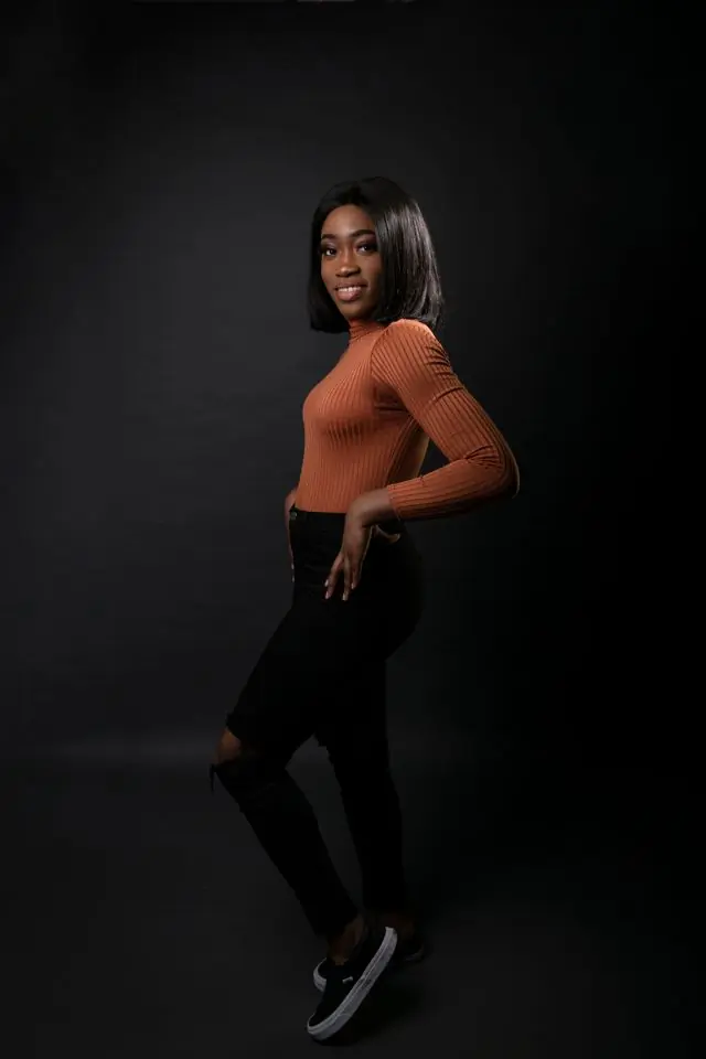 A model in a rust knit against a dark ground