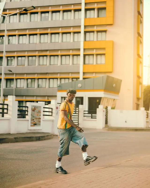 Someone walking past a yellow building at dusk