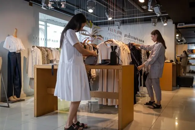 Two people browsing a rail in a bright shop