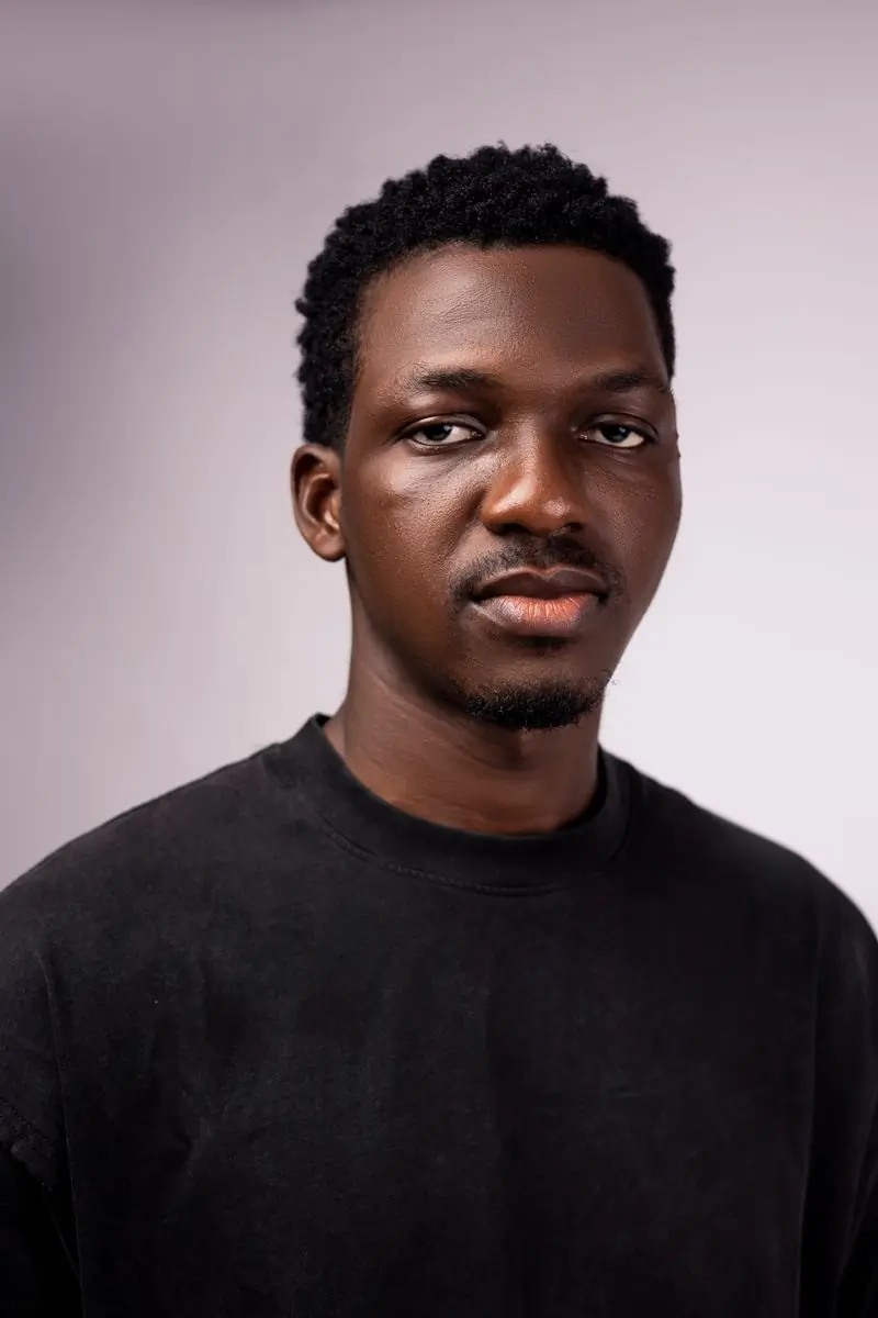 A member of staff in a black tee against a pale wall