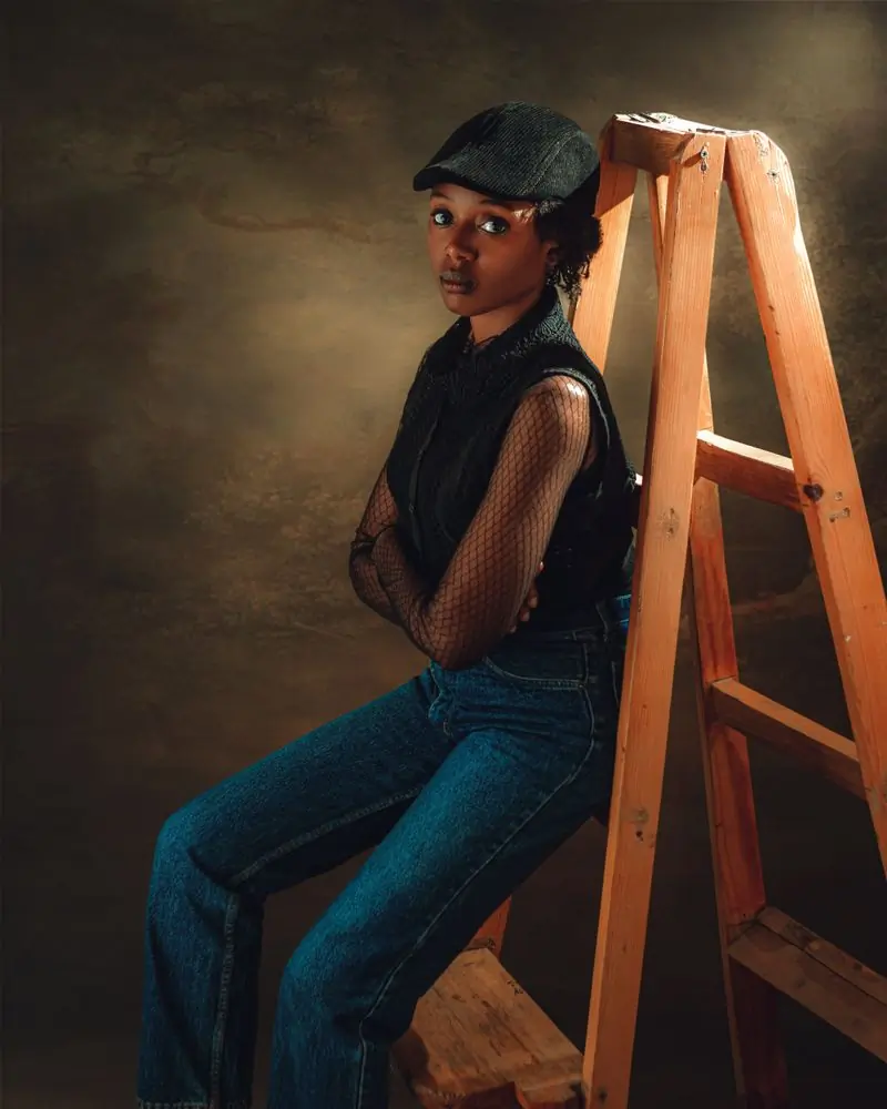 A member of staff leaning on a wooden ladder in a studio