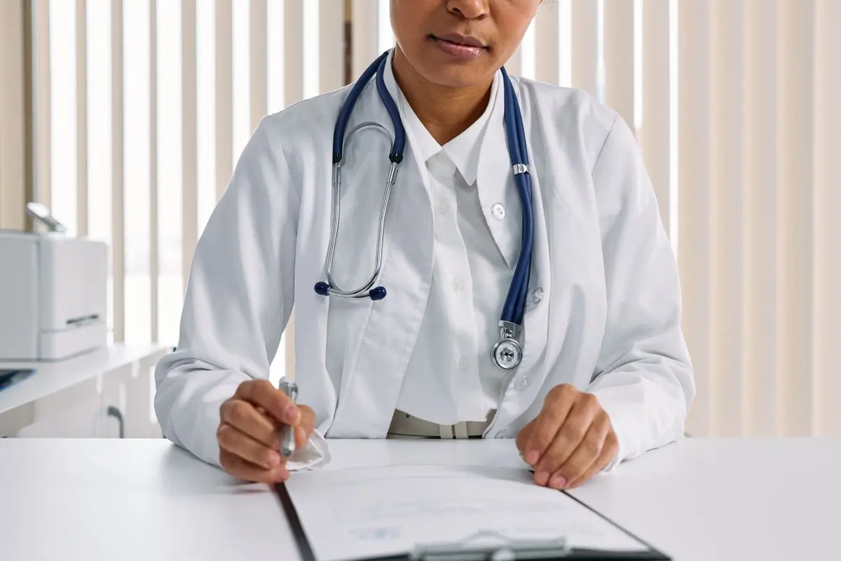 A doctor writing up notes at the consulting desk