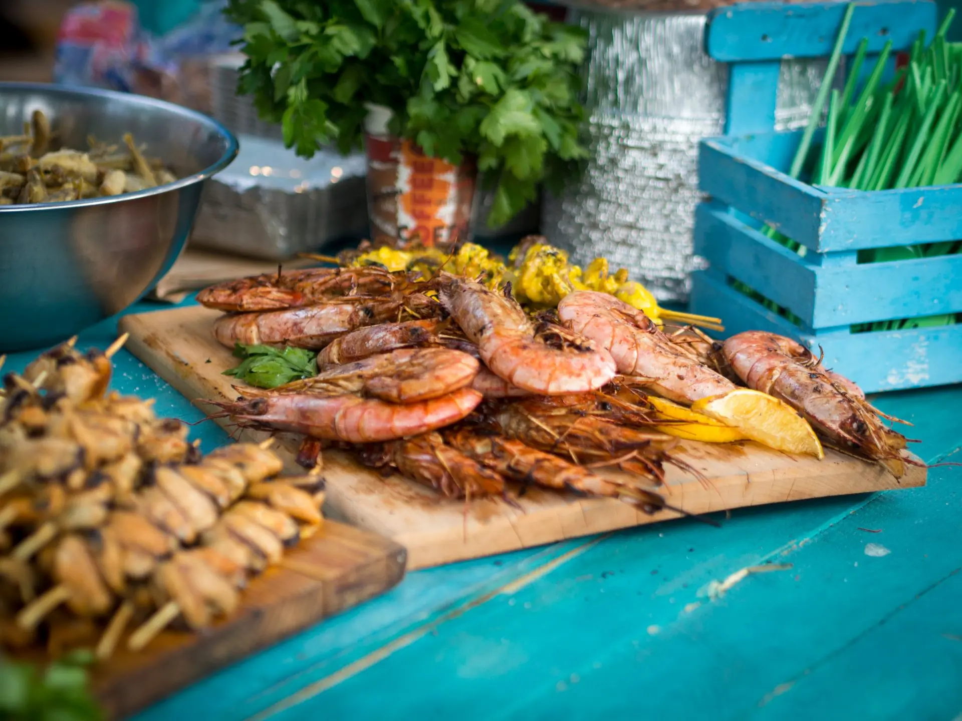 Grilled seafood laid out on a board beside a crate of ice