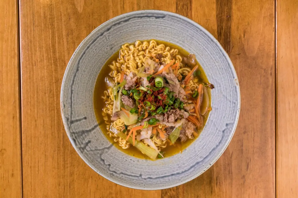 A ceramic bowl of coconut laksa with noodles and prawns