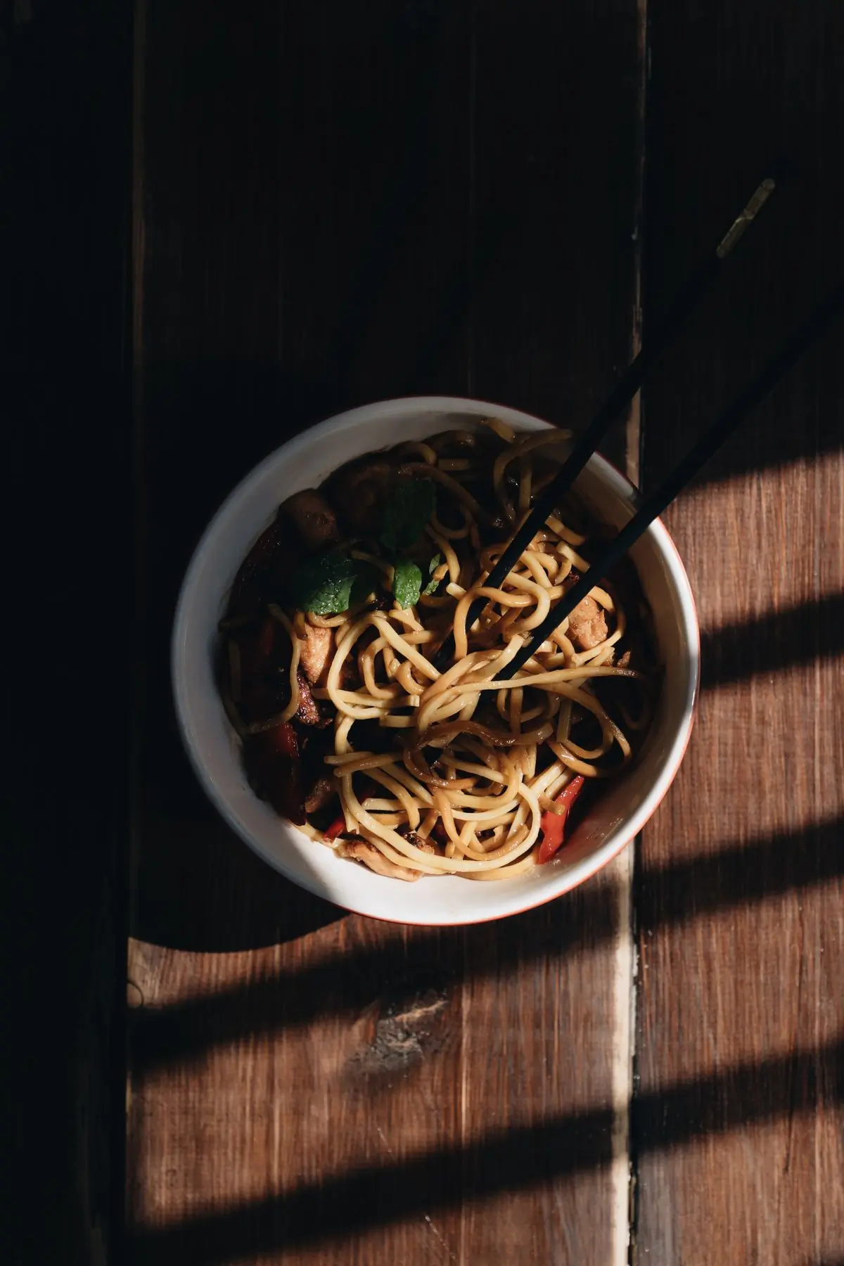 A bowl of noodles in a shaft of hard light