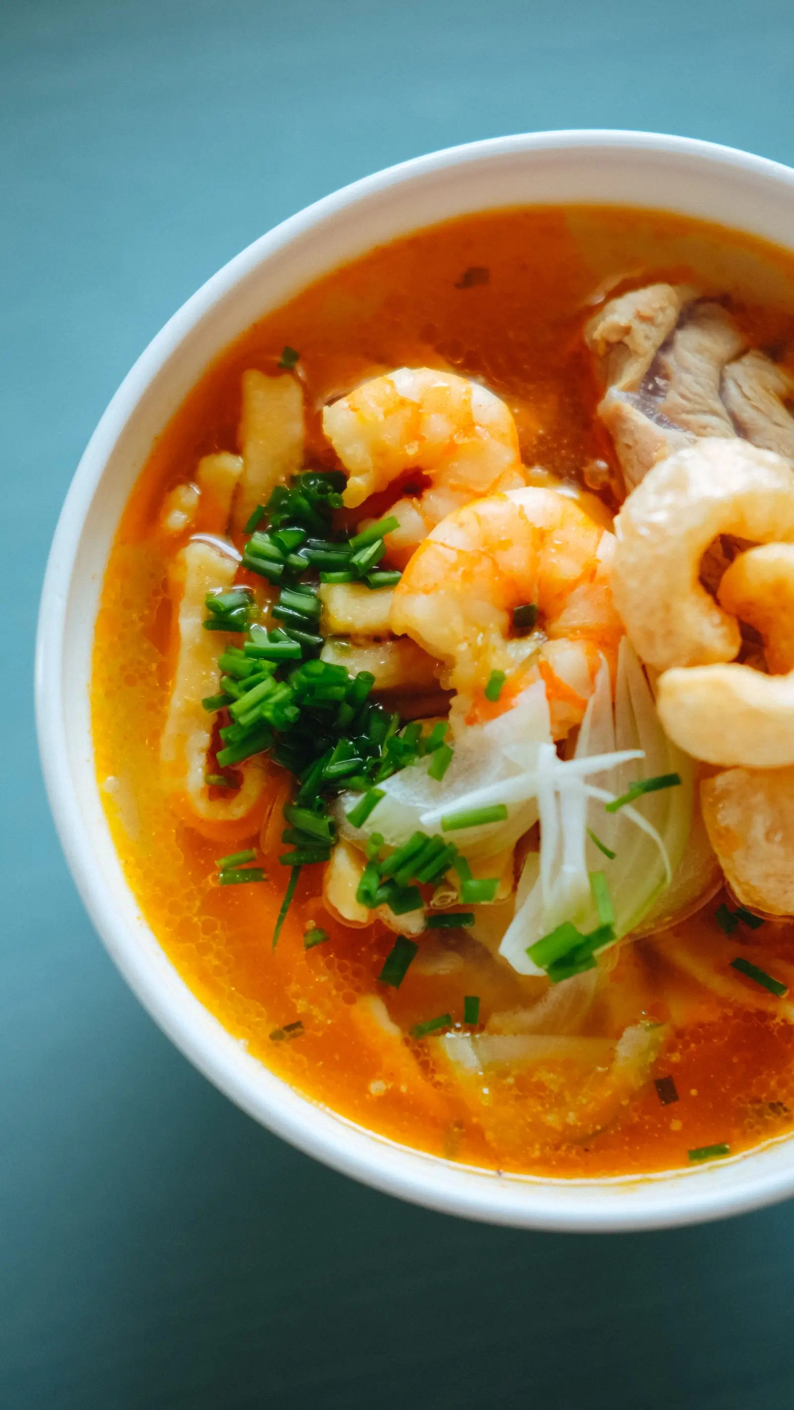A bowl of prawn noodles in broth photographed from directly above