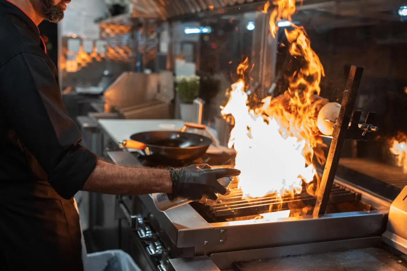 A cook working over an open flame at the pass