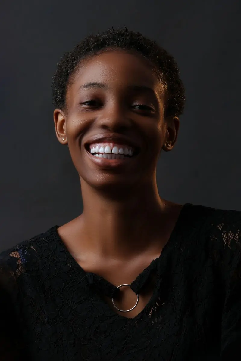 A smiling woman photographed against a dark ground