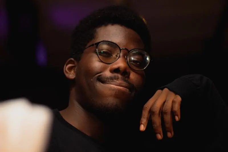 A man wearing glasses photographed against a dark ground