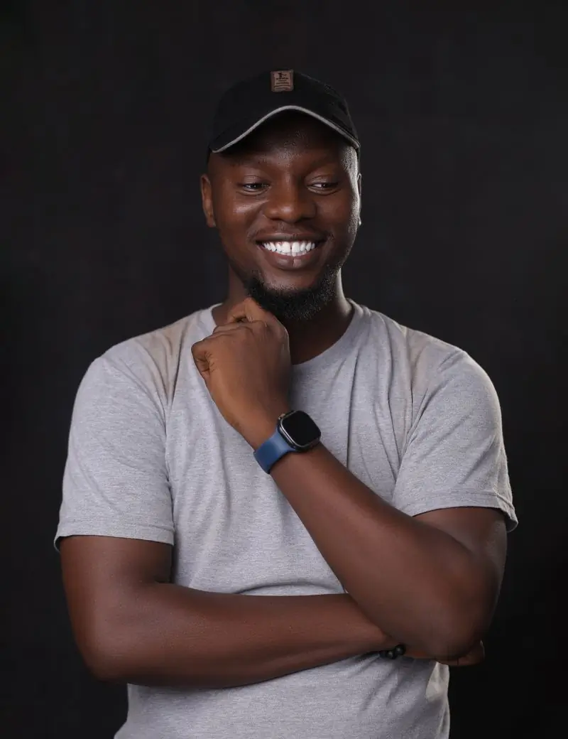 A smiling man in a grey shirt and dark hat