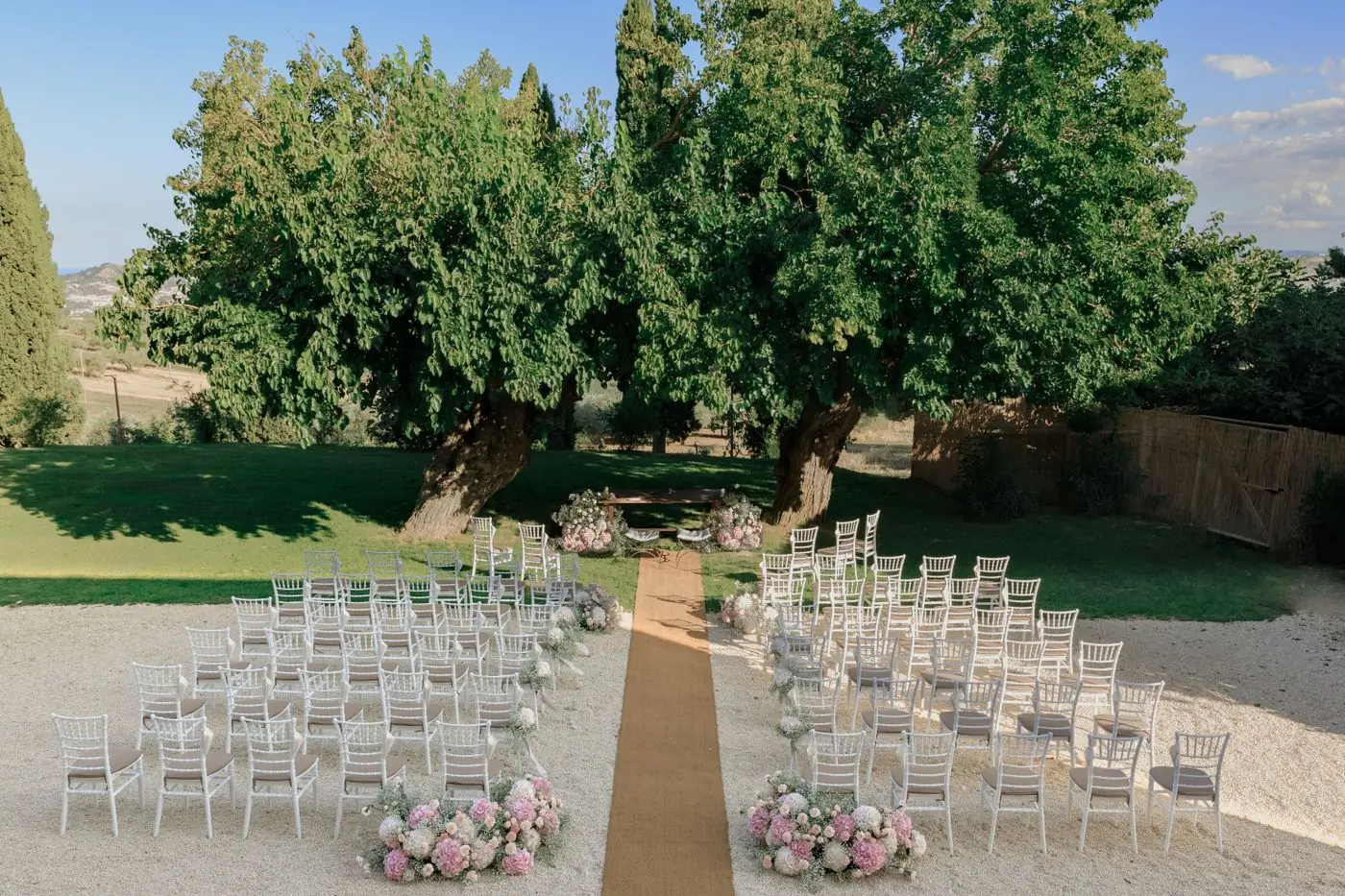 White chairs set out in rows in an orchard for an outdoor ceremony