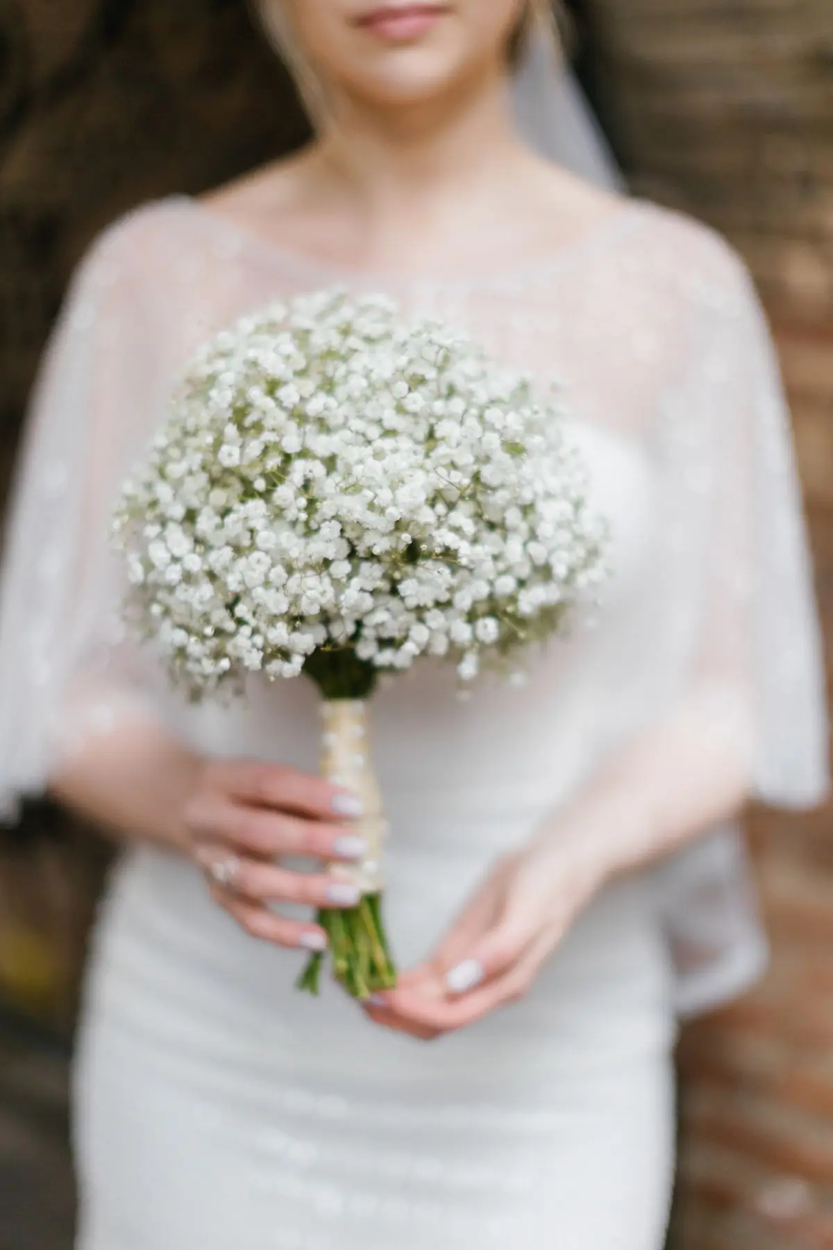 A bride holding a loose bouquet of baby's breath