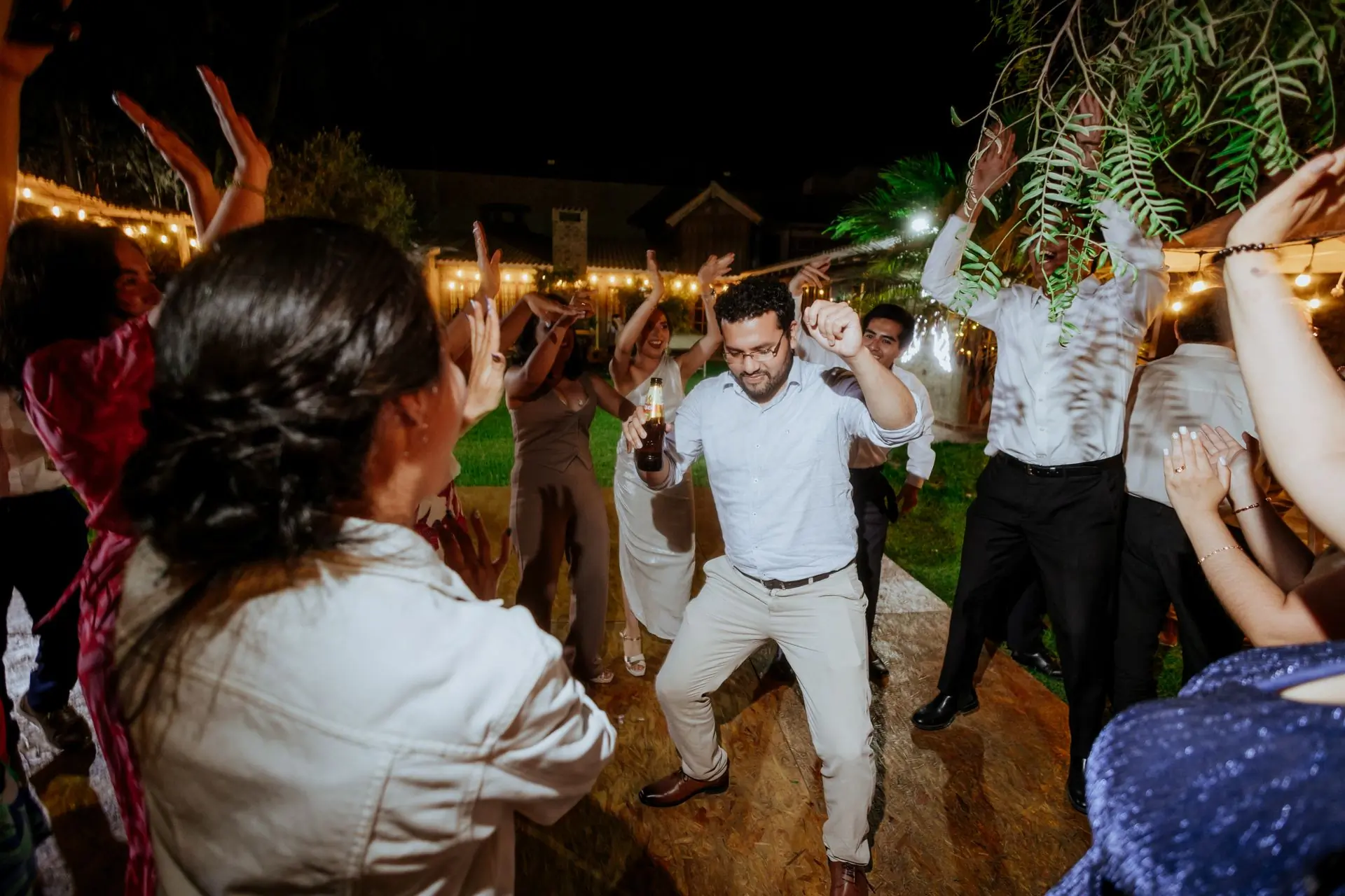 Guests dancing under strings of light at an outdoor wedding reception
