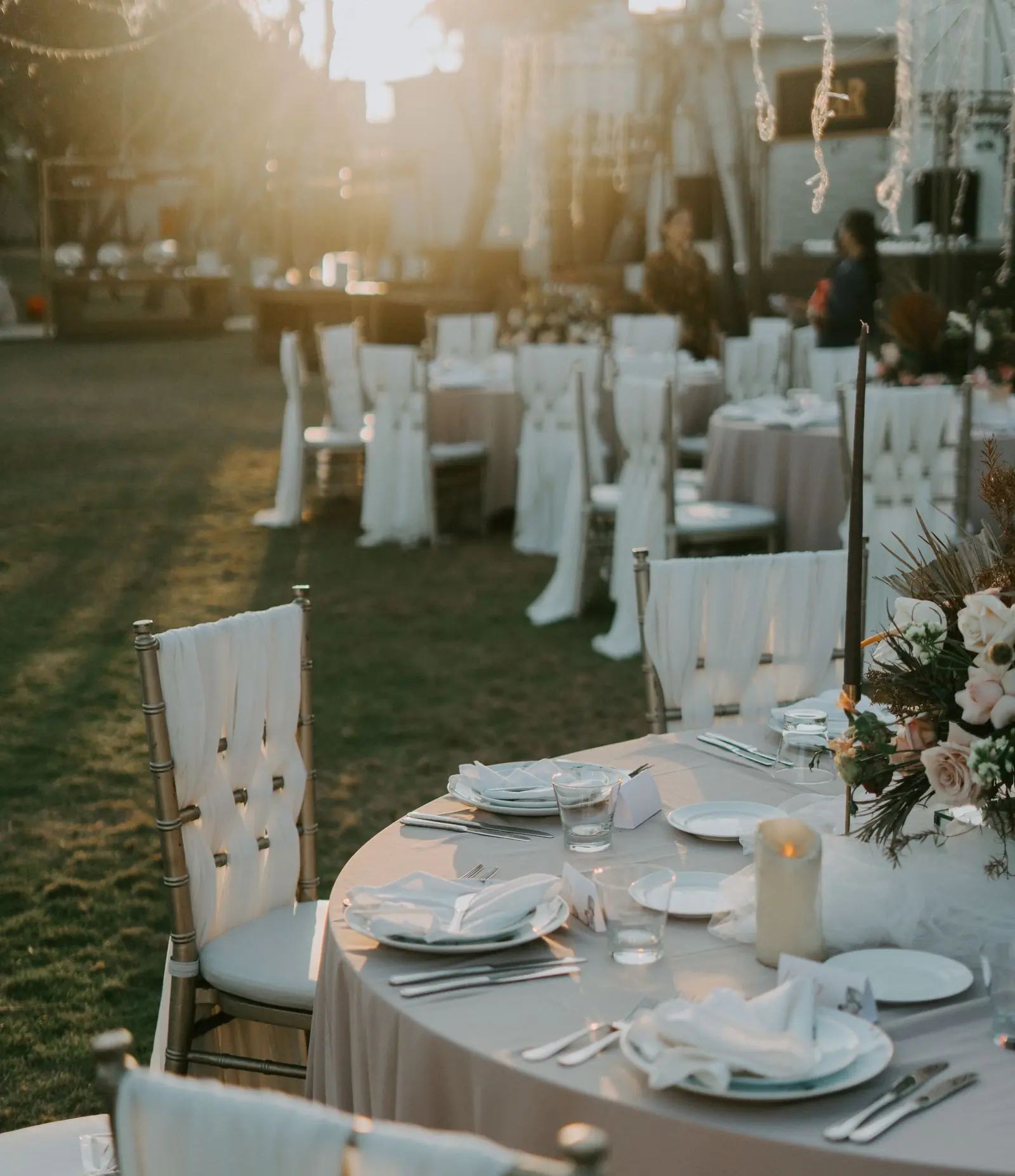 Chairs dressed in white linen set out on grass for a wedding ceremony