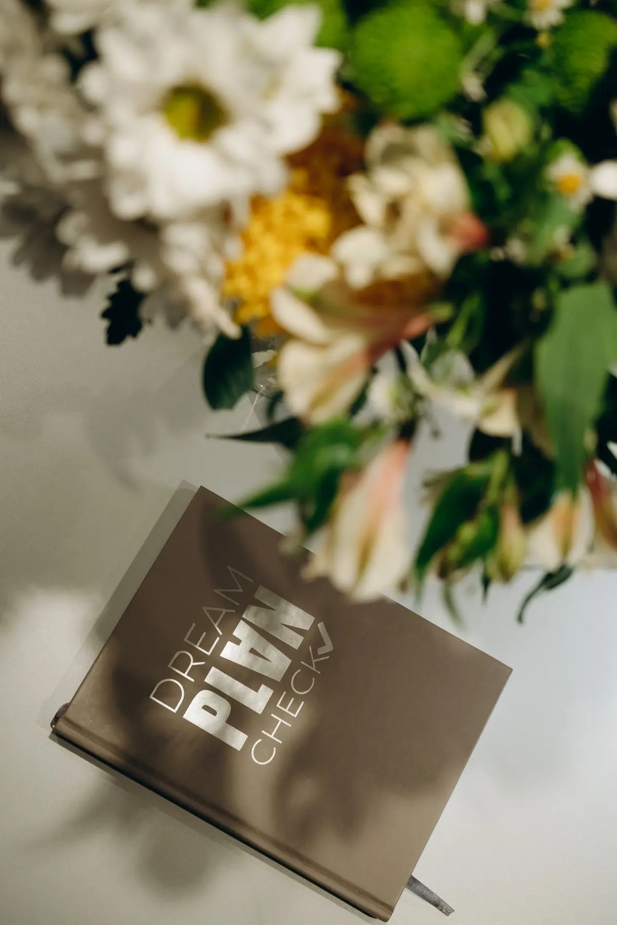A planner's notebook resting behind a low arrangement of soft white flowers
